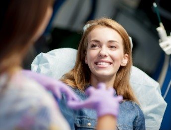 patient smiling at team member while laying in dental chair in Worcester